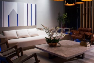 Com elementos modernos de design como luminárias em estilo industrial e o sofá com destaque para obra de arte