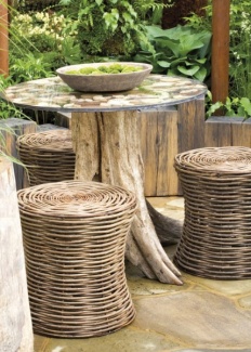 Esse para jardim em estilo rústico: bancos de cesto e a mesa de tronco de árvore com tampo de vidro.