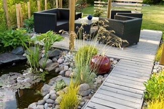 Aqui foi feito um laguinho decorado com pedras, e separado por um rústico caminho de deck que ruma para a área das cadeiras.