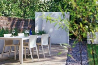 Caminho de brita e muro branco que separa a área gourmet, da área de um chuveiro, trazendo mais privacidade para a visita.