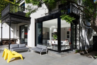 O contraste entre os bancos amarelos e o conjunto de estofados para a área externa dão personalidade e quebram o cinza.