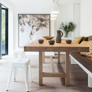 Na sala de jantar com pegada safari, tem mesa de madeira e canto alemão em tons terrosos e mostarda nas almofadas.