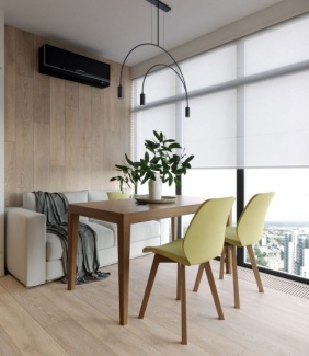 Sofá branco na área de jantar compõe o ambiente, e mesa relativamente pequena com duas cadeiras em amarelo.