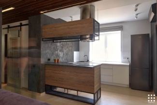 Esta cozinha tem fogão em ilha com revestimento em madeira, e o balcão da pia branco.