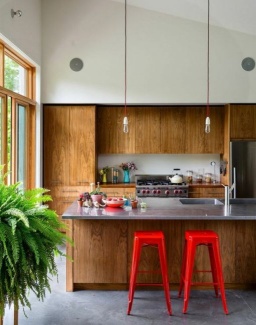 Ilha de aço, com estrutura de madeira, e madeira também nos armários da cozinha.