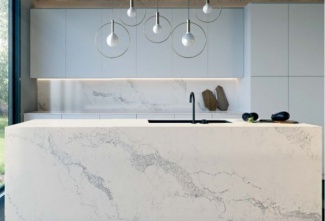 Granito branco em toda a ilha, balcão e parede da pia, nesta cozinha que também possui armários planejados brancos.