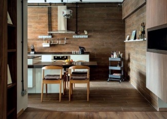 Revestimento do piso e parede são de porcelanato que reproduzem madeira, pia e balcão da ilha em granito preto com armários brancos.