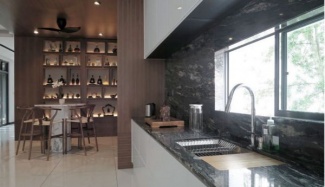 Balcão e parede de pia em granito verde, armários da cozinha brancos e estante em madeira.