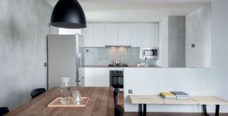 Cimento nas paredes e armários brancos para ampliar o espaço.