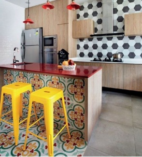 Ilha em pedra vermelha, e pia branca com revestimento de ladrilhos, armários de madeira.