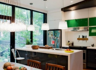 Cozinha com ilha com balcão branco e armários inferiores em aço laqueado preto, e armário superior em vidros verdes como ponto focal.