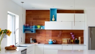 Cozinha com armários e balcão brancos, parede revestida de porcelanato que reproduz madeira e nichos azuis com destaque