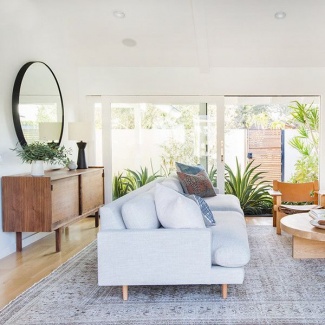 Aqui sofá branco, com deliciosas almofadas, móvel de apoio, centro e cadeira de madeira para compor a sala.