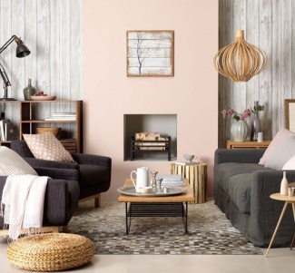 Parede em tom de rosa antigo e madeira clara, tapete natural, puff de palha e centro de madeira para equilibrar a cor do sofá e das poltronas.