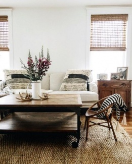 Cortinas e tapete em tramas naturais, sofá branco, centro de ferro e madeira e cadeira de vime.