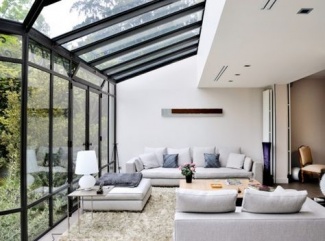 Sala com iluminação natural, predominantemente branca com sofás brancos, tapete de linha e centro de madeira.