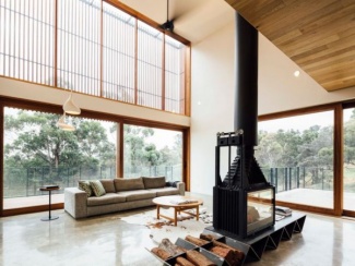 lareira industrial numa sala generosa e muito iluminadas, sofá cinza e centro de madeira sobre um tapete de pele natural.