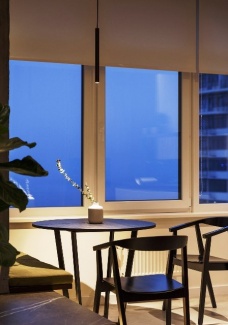 Apartamento Industrial - Duas cadeiras de jantar e um banco para apreciar a vista da janela.